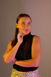 Photo of Beautiful woman in neon lights against grey background
