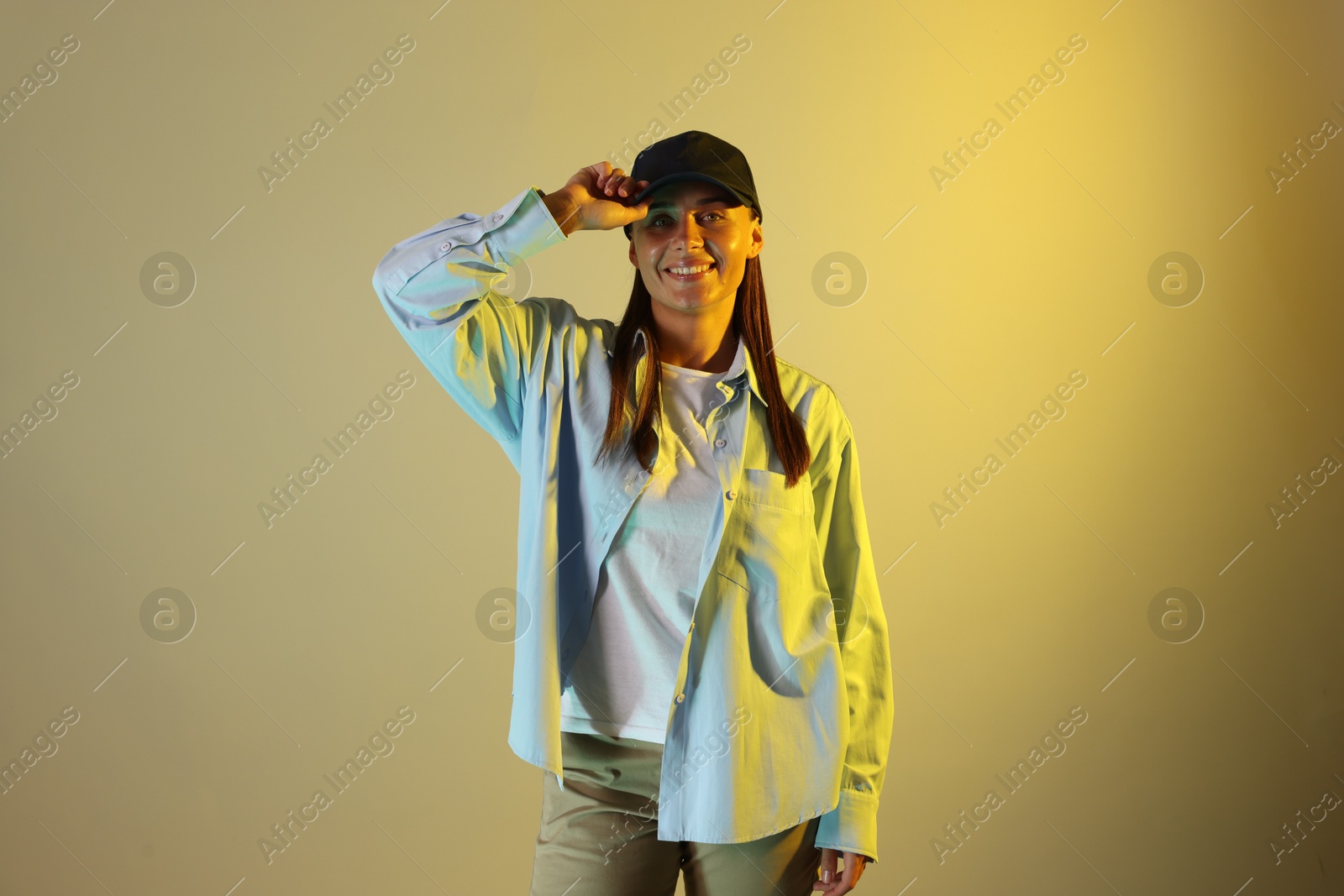 Portrait of smiling woman wearing baseball cap in neon lights against color background Photo of Portrait of smiling woman wearing baseball cap in neon lights against color background