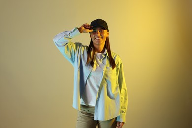 Photo of Portrait of smiling woman wearing baseball cap in neon lights against color background