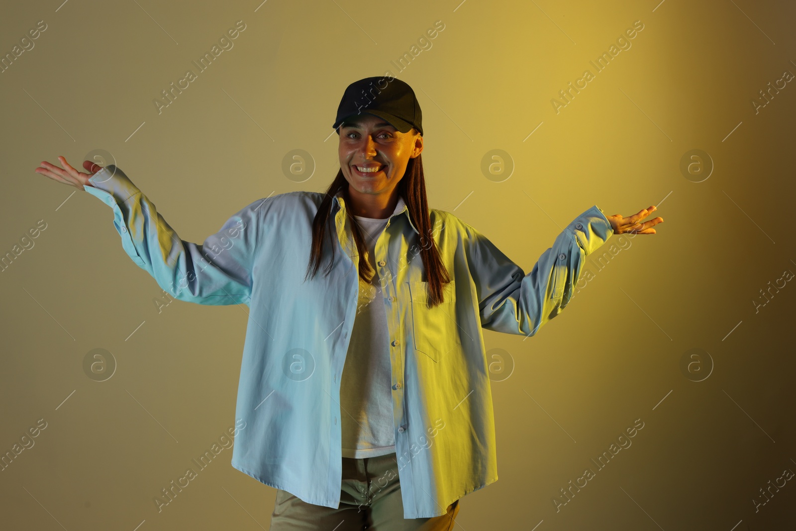 Portrait of smiling woman wearing baseball cap in neon lights against color background Photo of Portrait of smiling woman wearing baseball cap in neon lights against color background