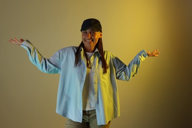 Photo of Portrait of smiling woman wearing baseball cap in neon lights against color background