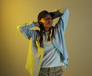 Photo of Beautiful woman wearing baseball cap in neon lights against color background