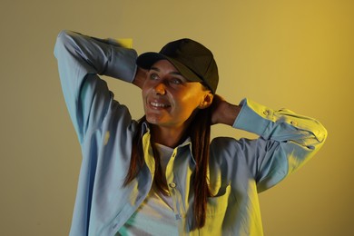 Photo of Smiling woman wearing baseball cap in neon lights against color background
