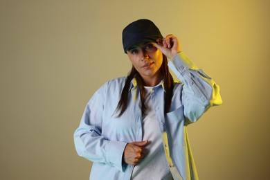 Photo of Portrait of beautiful woman wearing baseball cap in neon lights against color background