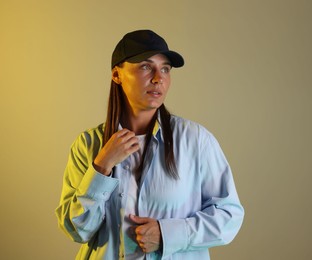 Photo of Beautiful woman wearing baseball cap in neon lights against color background