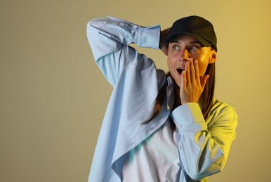 Photo of Emotional woman wearing baseball cap in neon lights against color background