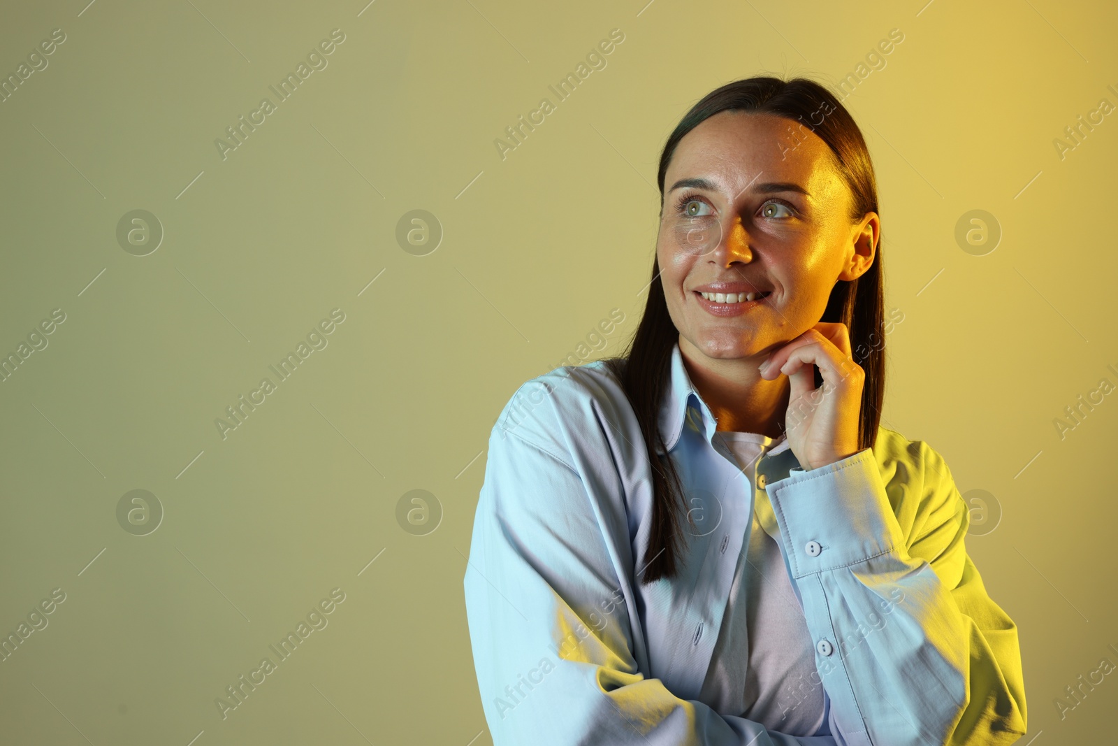 Smiling woman in neon lights against color background. Space for text Photo of Smiling woman in neon lights against color background. Space for text