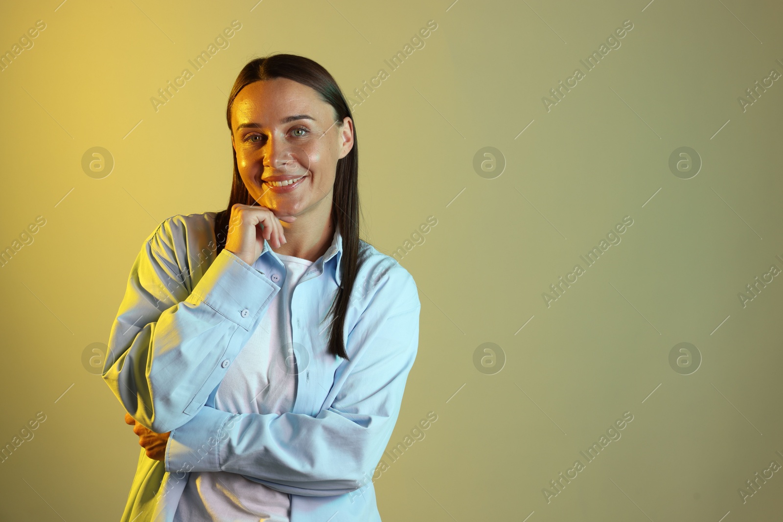 Smiling woman in neon lights against color background. Space for text Photo of Smiling woman in neon lights against color background. Space for text