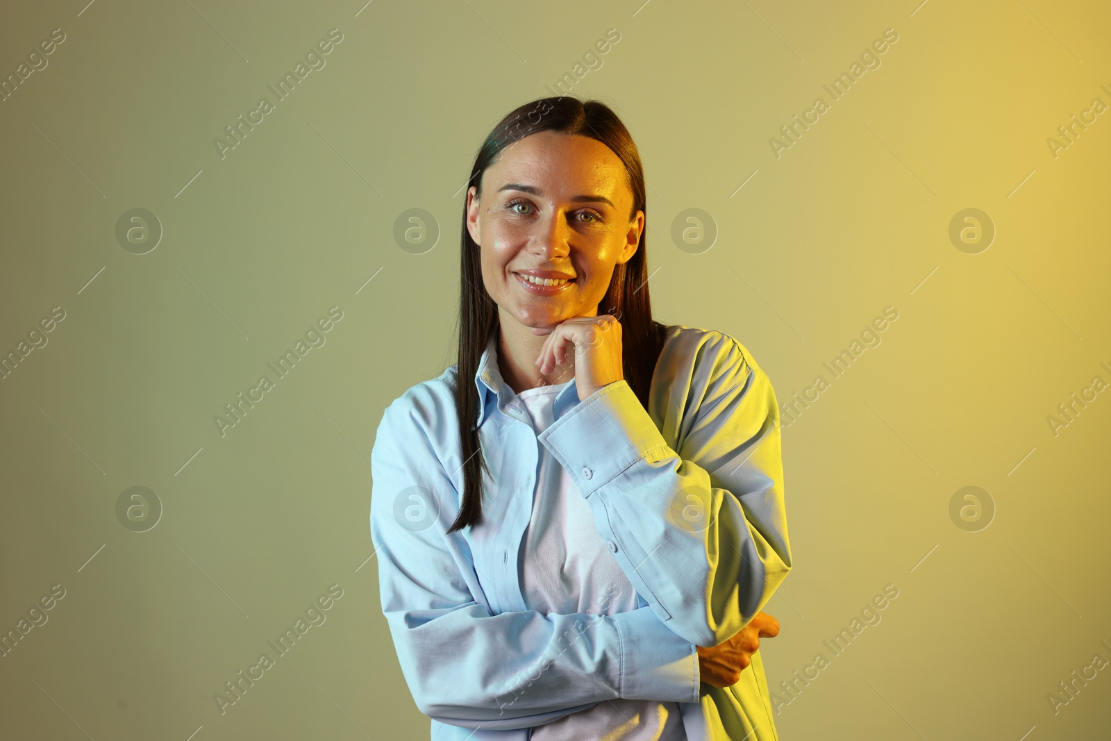 Smiling woman in neon lights against color background Photo of Smiling woman in neon lights against color background