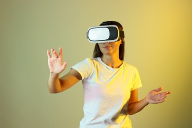 Photo of Woman using virtual reality headset in neon lights against color background