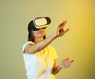 Photo of Woman using virtual reality headset in neon lights against color background