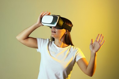 Photo of Woman using virtual reality headset in neon lights against color background
