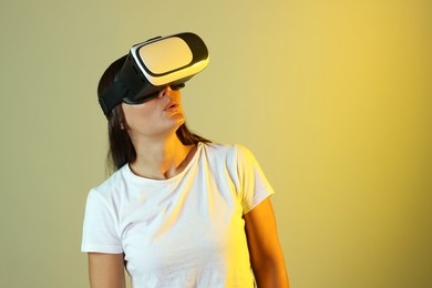 Photo of Emotional woman using virtual reality headset in neon lights against color background