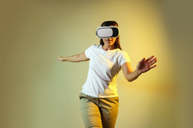 Photo of Woman using virtual reality headset in neon lights against color background