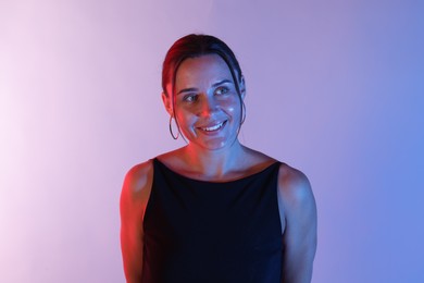 Photo of Smiling woman in neon lights against color background