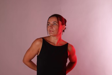 Photo of Beautiful woman in neon lights against pink background