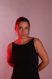 Photo of Portrait of beautiful woman in neon lights against pink background