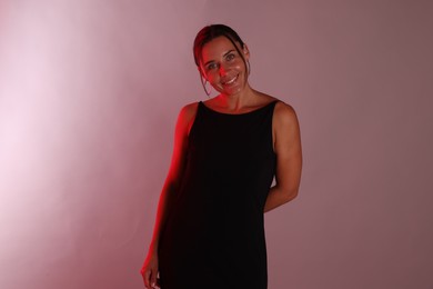 Photo of Smiling woman in neon lights against pink background