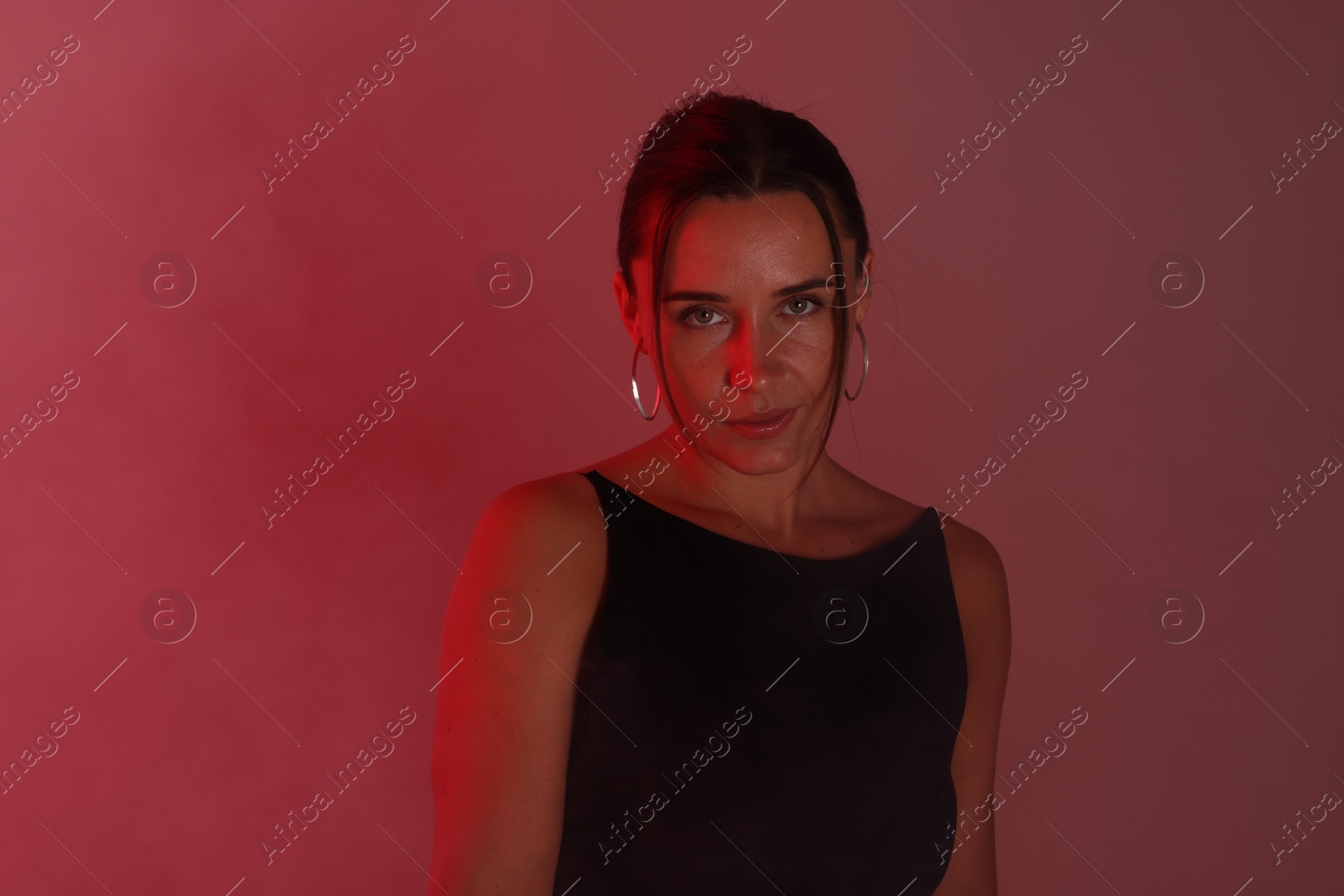Beautiful woman in neon lights against red background Photo of Beautiful woman in neon lights against red background