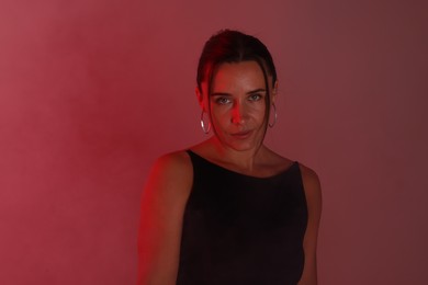 Photo of Beautiful woman in neon lights against red background