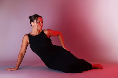 Photo of Beautiful woman wearing dress posing in neon lights against color background