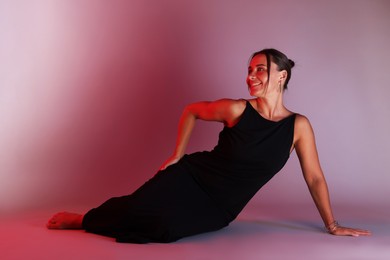 Photo of Smiling woman wearing dress posing in neon lights against color background