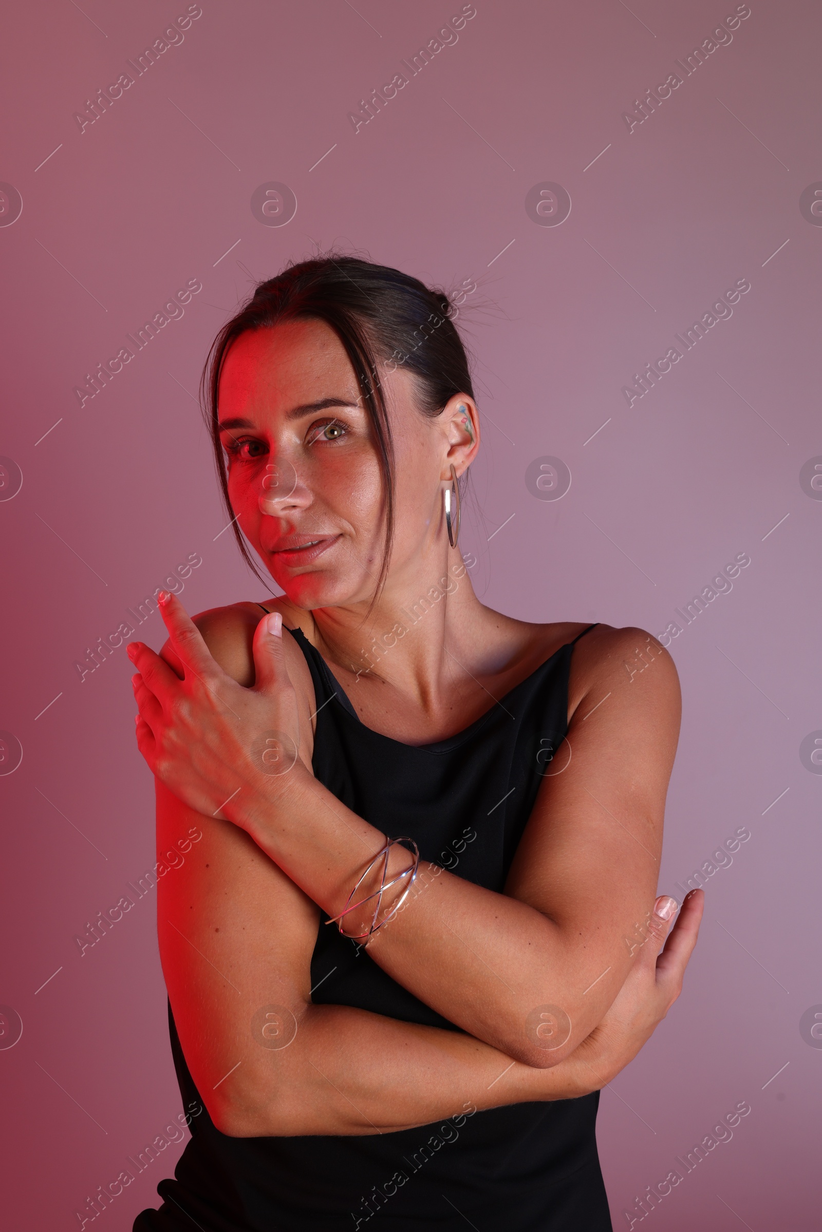 Portrait of beautiful woman with bracelet in neon lights against color background Photo of Portrait of beautiful woman with bracelet in neon lights against color background