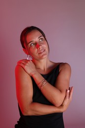 Photo of Beautiful woman with bracelet in neon lights against color background