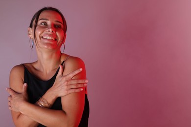 Photo of Smiling woman in neon lights against color background. Space for text