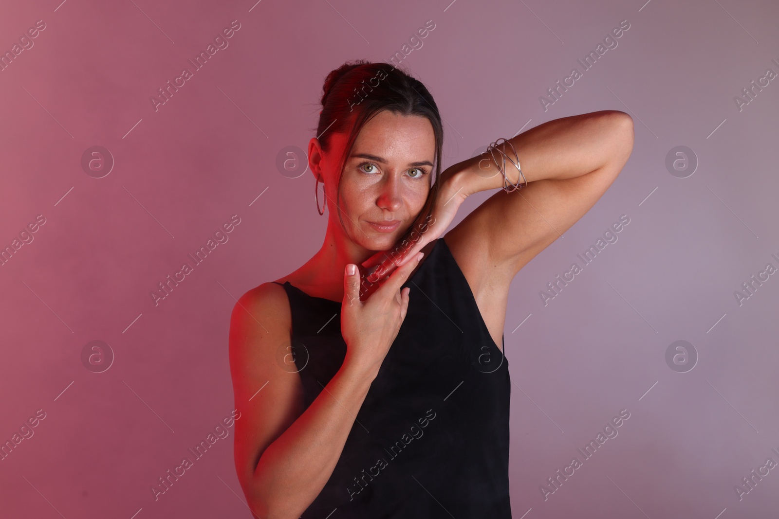 Beautiful woman with bracelet in neon lights against color background Photo of Beautiful woman with bracelet in neon lights against color background