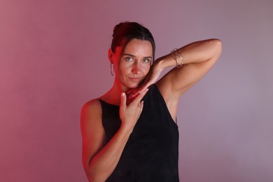 Photo of Beautiful woman with bracelet in neon lights against color background