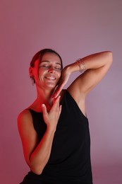 Photo of Smiling woman with bracelet in neon lights against color background
