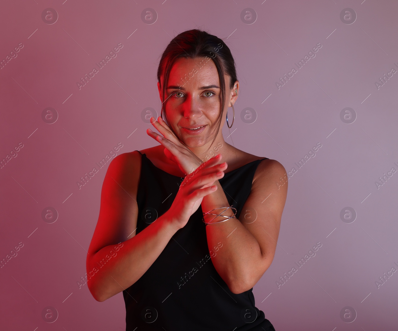 Photo of Beautiful woman with bracelet in neon lights against color background