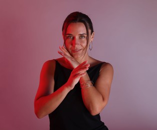 Photo of Beautiful woman with bracelet in neon lights against color background