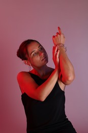Photo of Beautiful woman with bracelet in neon lights against color background