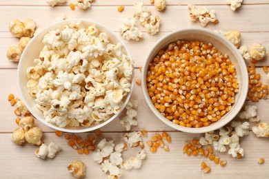 Photo of Tasty popcorn and corn kernels on white wooden table, flat lay