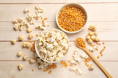Photo of Tasty popcorn and corn kernels on white wooden table, flat lay