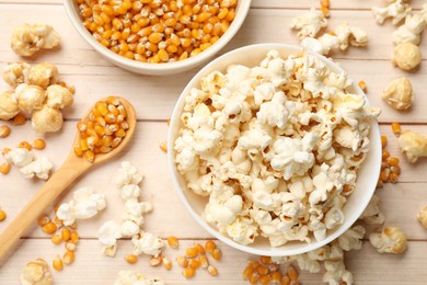 Photo of Tasty popcorn and corn kernels on white wooden table, flat lay