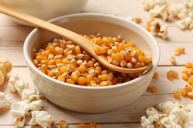 Photo of Corn kernels and tasty popcorn on white wooden table, closeup