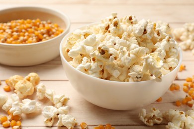 Photo of Tasty popcorn and corn kernels on white wooden table, closeup