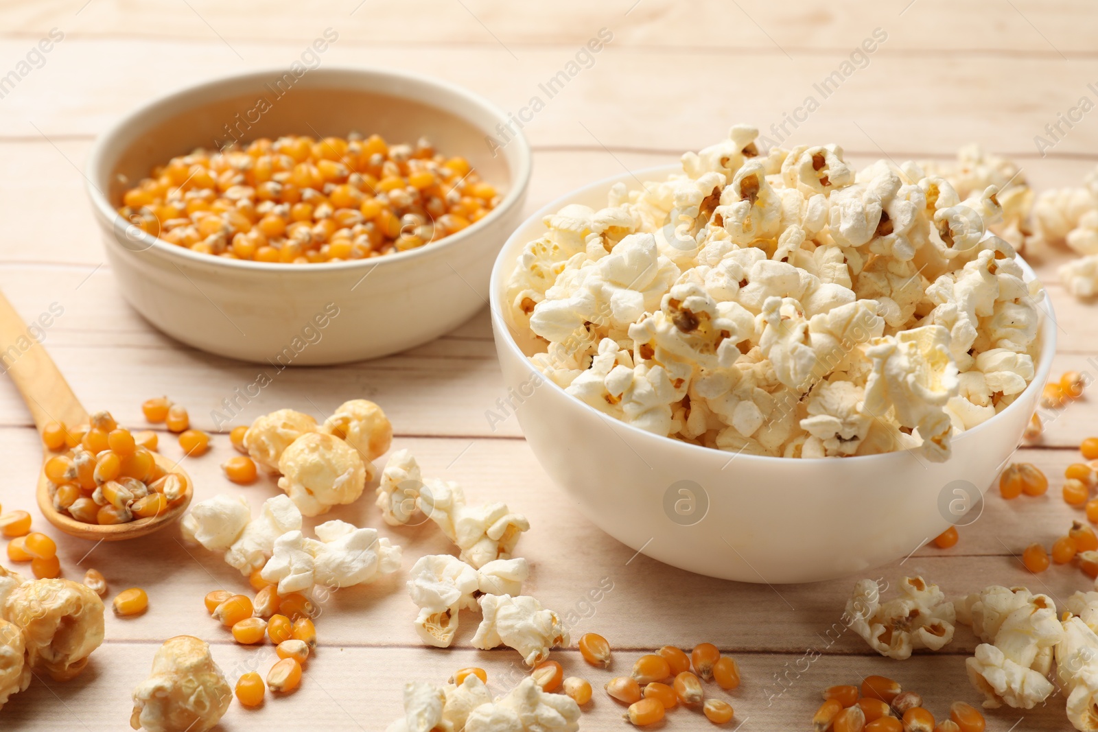 Tasty popcorn and corn kernels on white wooden table, closeup Photo of Tasty popcorn and corn kernels on white wooden table, closeup