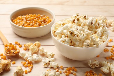 Photo of Tasty popcorn and corn kernels on white wooden table, closeup
