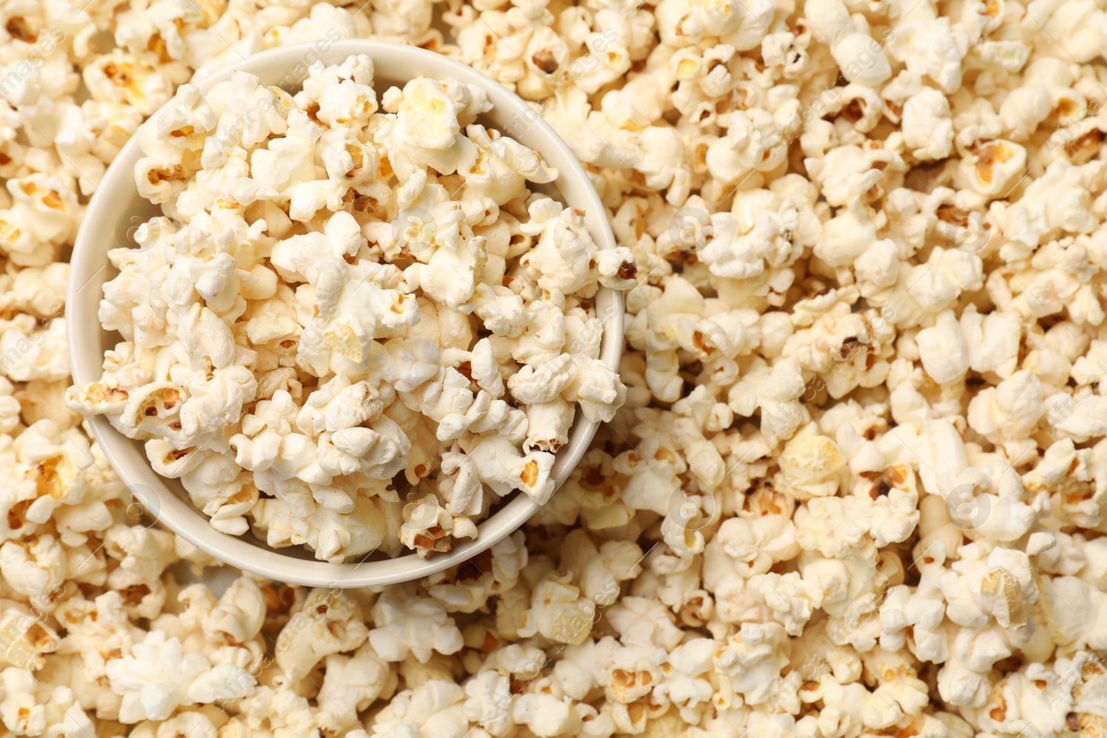 Photo of Tasty popcorn and bowl as background, closeup