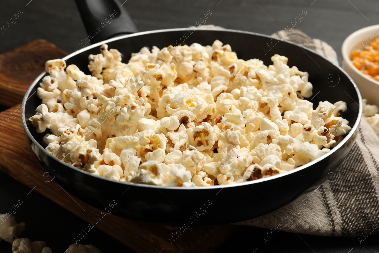 Tasty popcorn in frying pan on black table, closeup Photo of Tasty popcorn in frying pan on black table, closeup