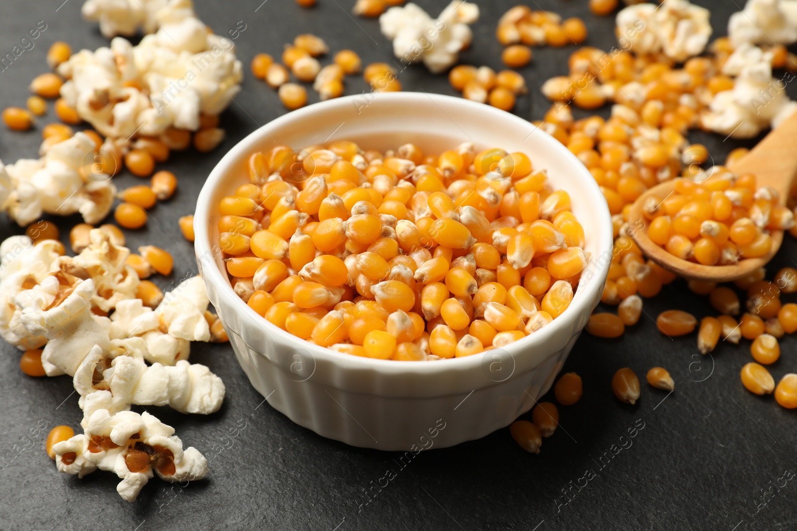 Corn kernels and tasty popcorn on black table, closeup Photo of Corn kernels and tasty popcorn on black table, closeup