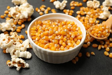 Photo of Corn kernels and tasty popcorn on black table, closeup