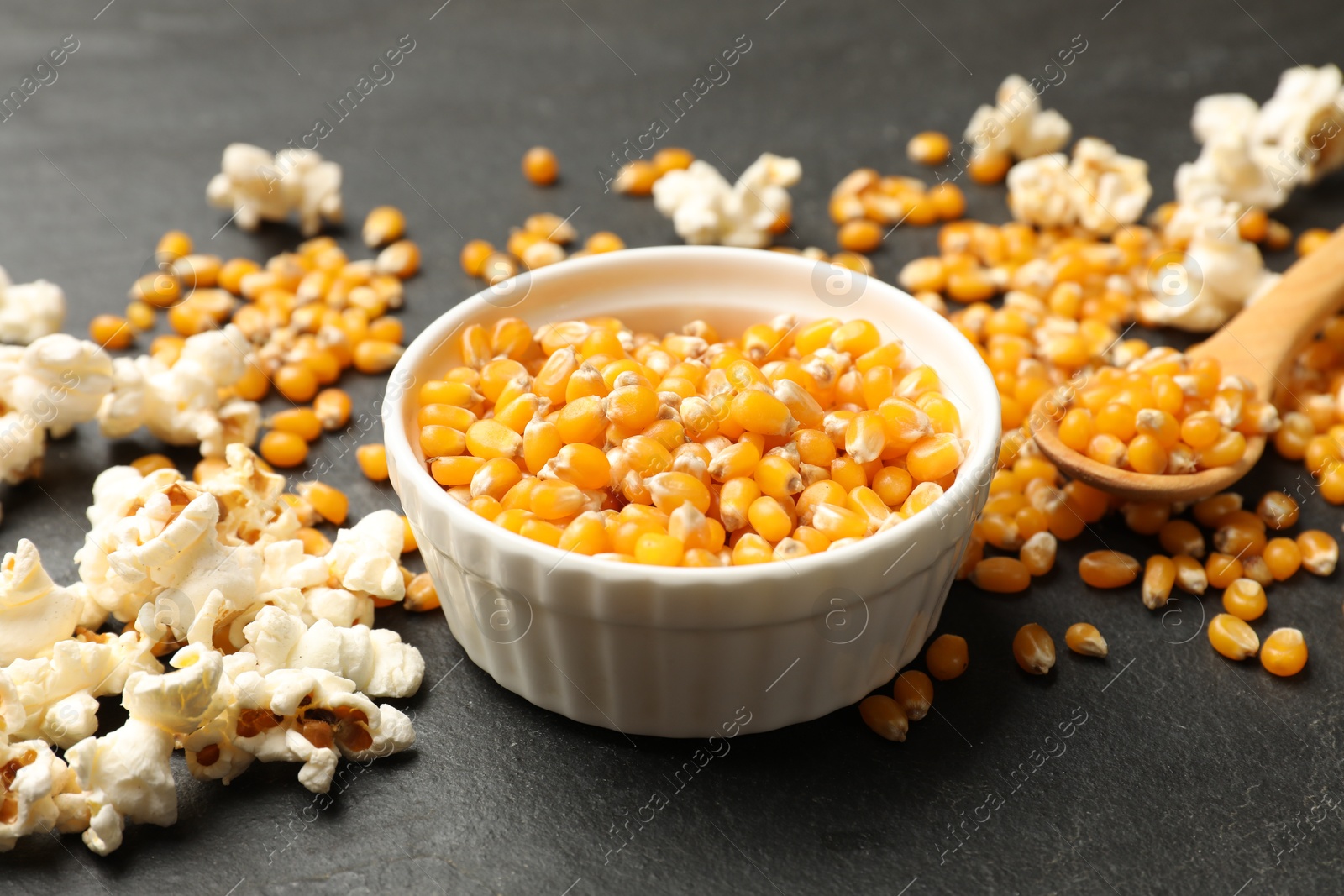 Corn kernels and tasty popcorn on black table, closeup Photo of Corn kernels and tasty popcorn on black table, closeup