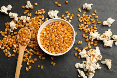 Photo of Corn kernels and tasty popcorn on black table, flat lay