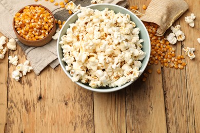 Photo of Tasty popcorn and corn kernels on wooden table, flat lay. Space for text
