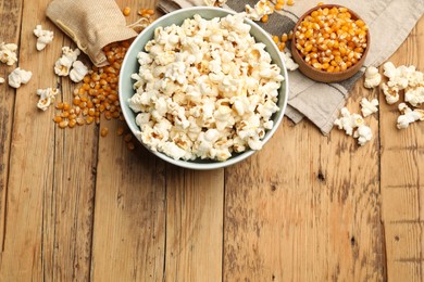 Photo of Tasty popcorn and corn kernels on wooden table, flat lay. Space for text